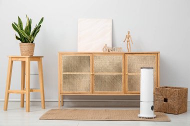 Oturma odasındaki çekmecelerin yanındaki halının üzerinde hava nemlendirici var.