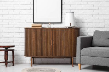 Hava nemlendirici ve oturma odasındaki beyaz tuğla duvarın yanındaki çekmeceler üzerine kitaplar.