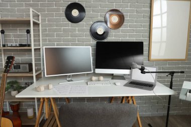 Kayıt stüdyosunda dizüstü bilgisayarı, monitörü ve mikrofonu olan işyeri