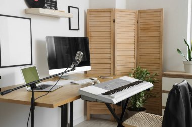Kayıt stüdyosunda bilgisayar, sentezleyici ve mikrofon bulunan işyeri