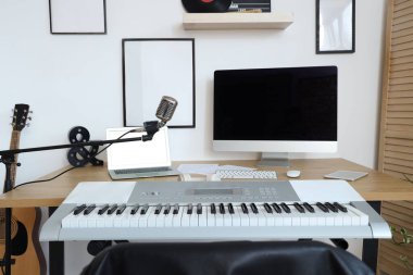 Kayıt stüdyosunda bilgisayar, sentezleyici ve mikrofon bulunan işyeri