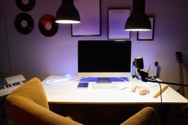 Karanlık kayıt stüdyosunun içinde işyeri, mikrofon ve parlayan lambalar var.