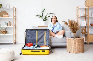 Düşünceli bayan turist valizini hazırlarken kontrol listesi yapıyor.