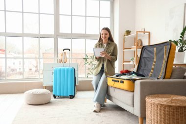 Evde bavul hazırlarken kontrol listesi hazırlayan kadın turist