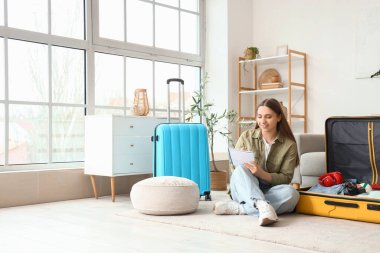 Evde bavul hazırlarken kontrol listesi hazırlayan kadın turist