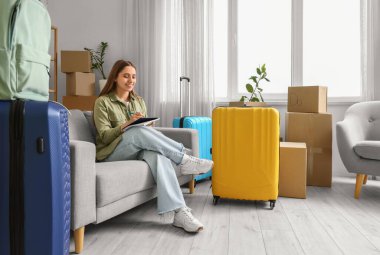 Bavullu genç bir kadın taşınma gününde odada kontrol listesi yapıyor.