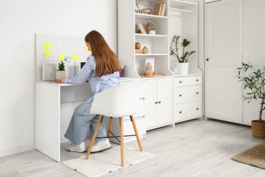 Genç bir kadın, merkez ofisindeki masada yapılacaklar listesi yapıyor.