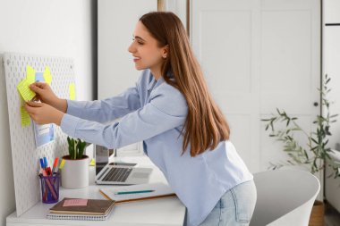 Genç bir kadın evdeki tahtada yapılacaklar listesi yapıyor.