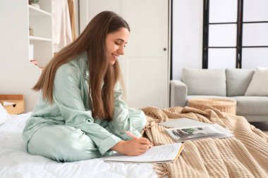 Genç bir kadın yatak odasında yapılacaklar listesi yapıyor.