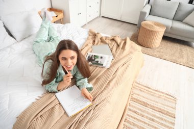 Düşünceli genç bir kadın yatak odasında yapılacaklar listesi yapıyor.