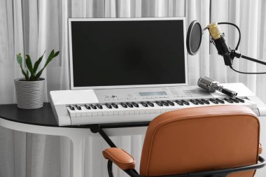 Kayıt stüdyosunda bilgisayar, sentezleyici ve mikrofon bulunan işyeri