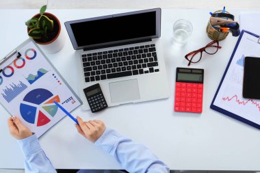 Masada diyagramlarla çalışan kadın muhasebecinin elleri.