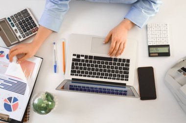 Masada dizüstü bilgisayarla çalışan kadın muhasebecinin elleri.