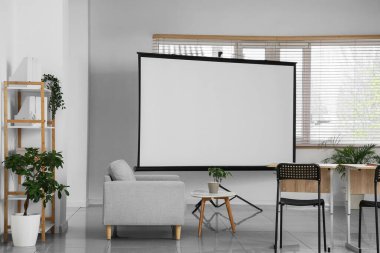 Boş projektör ekranı ve masaları olan boş sınıfın içi