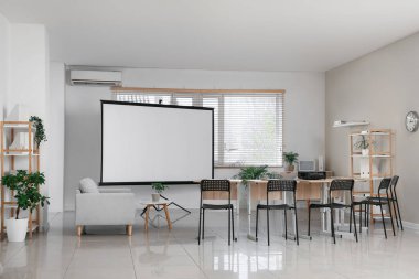 Boş projektör ekranı ve masaları olan boş sınıfın içi