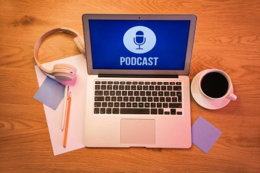 Podcast, kulaklık ve kahve fincanı olan dizüstü bilgisayar.