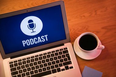 Bilgisayarda podcast ve kahve fincanı var.
