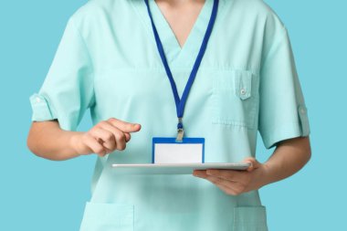 Rozeti ve tableti mavi arka planda olan kadın kardiyolog, yakın plan.