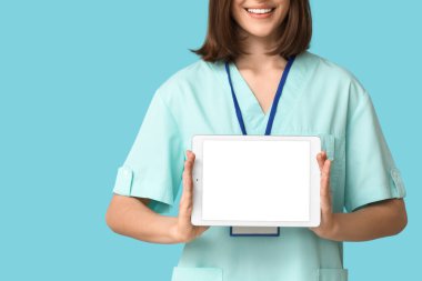 Mavi arka planda rozeti ve tableti olan mutlu kadın kardiyolog, yakın plan.