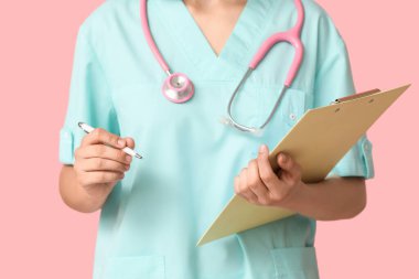 Pembe arka planda steteskop ve panoya sahip kadın kardiyolog, yakın plan.