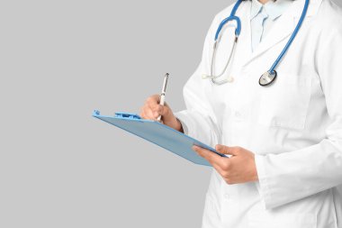 Steteskop ve gri arka planda panosu olan kadın kardiyolog, yakın plan.