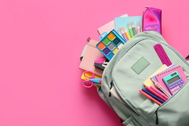Pembe arka planda farklı kırtasiye malzemesi içeren şık bir okul çantası.