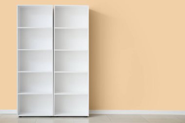 Bej duvarın yanında boş beyaz raf ünitesi.