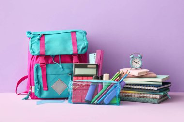 Alarm saati, okul çantası ve eflatun kaplamalı kalem çantası.