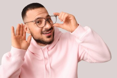 Genç adam arka planda bir şeyler duymaya çalışıyor, yakın plan.