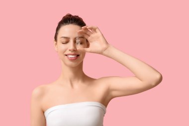 Pembe arka planda ampulü olan gülümseyen genç kadın.