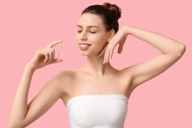 Pembe arka planda ampulü olan gülümseyen genç kadın.