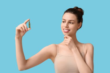 Mavi arka planda ampulü olan güzel genç bir kadın.