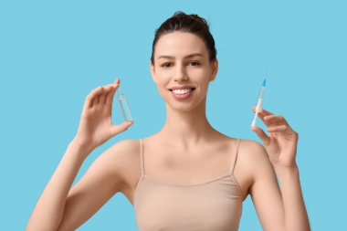 Mavi arka planda ampul ve şırıngası olan güzel genç bir kadın.