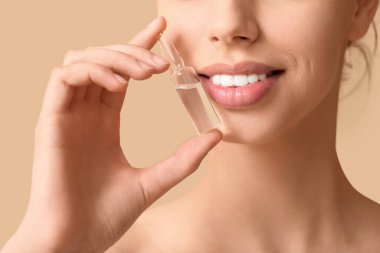 Kahverengi arka planda ampulü olan genç bir kadın, yakın plan.