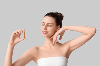 Gri arka planda ampulü olan güzel bir genç kadın.