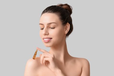 Gri arka planda ampulü olan güzel bir genç kadın.