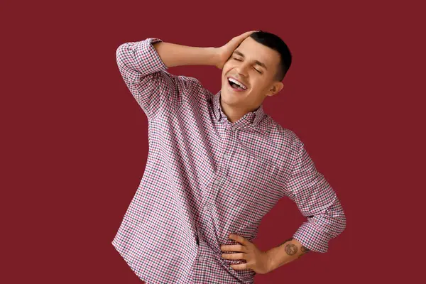 Kırmızı arka planda gülen mutlu genç adamın portresi