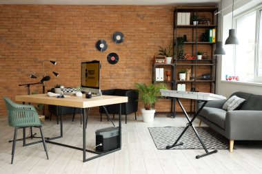 Podcaster 'ın atölyesinin içinde iş yeri, kanepe ve sentezleyici var.