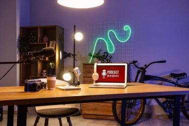 Podcaster 'ın atölyesinde dizüstü bilgisayarı, mikrofonları ve yanan lambaları olan işyeri