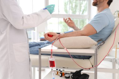 Genç adam klinikte doktorla kan bağışı yapıyor.