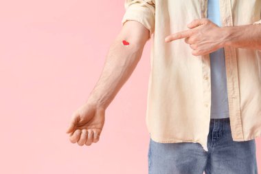 Erkek kan donörü pembe arka planda tıbbi yamaya bakıyor. Yakın plan.