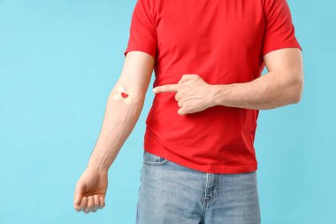 Erkek kan donörü mavi arka plandaki tıbbi bantlara bakıyor.