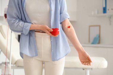 Kliniğe kan bağışladıktan sonra tıbbi bantları ve kalbi olan genç bir kadın.