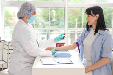 Kliniğe kan bağışladıktan sonra test tüplü genç kadın ve doktor.