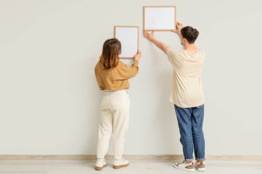 Işık duvarına boş çerçeveler asan genç bir çift.