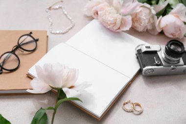 Boş kitap, fotoğraf makinesi ve bej grunge arka planda şakayık çiçekleri olan kompozisyon