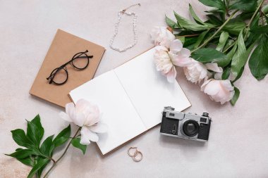 Boş kitap, fotoğraf makinesi ve bej grunge arka planda şakayık çiçekleri olan kompozisyon