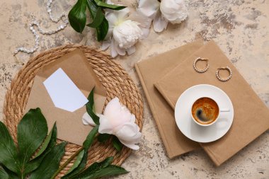 Kitaplı kompozisyon, hasır paspas, bir fincan kahve ve bej renginde şakayık çiçekleri, yakın plan.