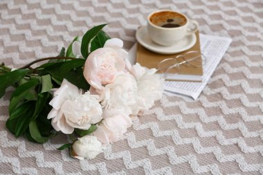 Bir fincan kitap, gözlük ve şakayık çiçekli kahve, yakın plan.