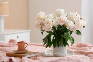 Kahve tepsisi, şakayık çiçekleri ve yatakta kitaplar.